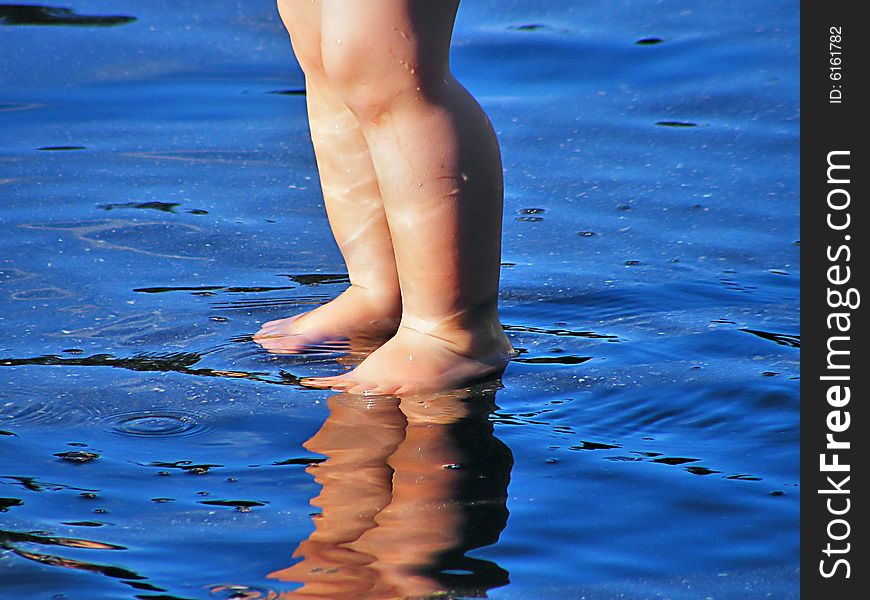 The legs of a child in the blue water. The legs of a child in the blue water.