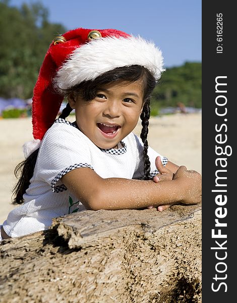 Little Thai girl with Christmas hat on a beach. Little Thai girl with Christmas hat on a beach