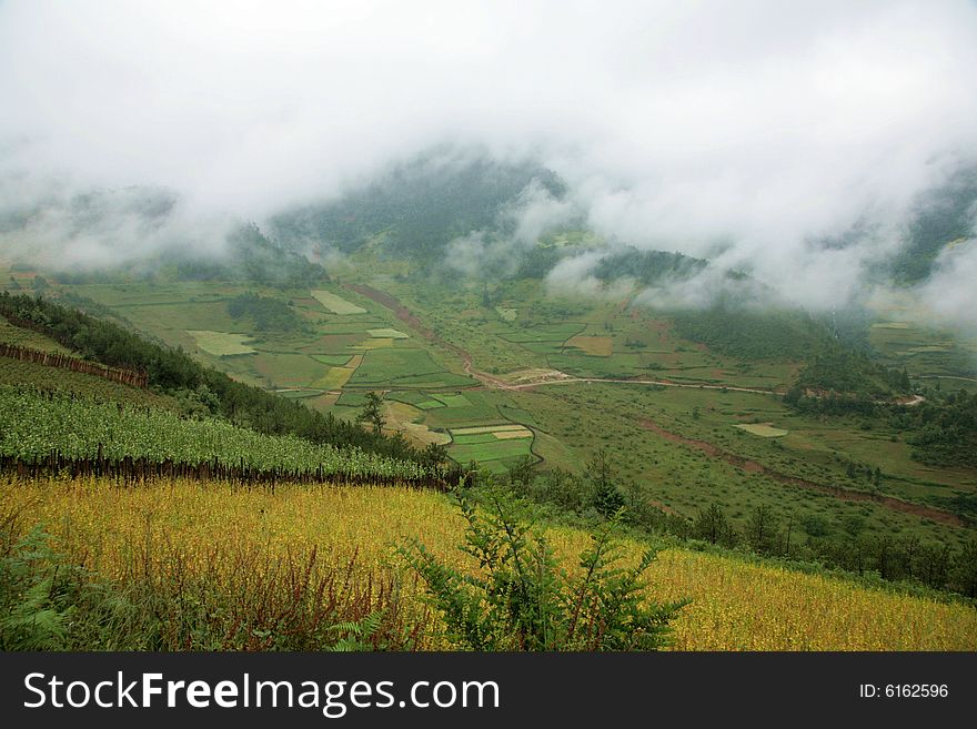 The photo is about Yunnan province of China, there is a large field in front of a mountain, there are some clouds in the sky. The photo is about Yunnan province of China, there is a large field in front of a mountain, there are some clouds in the sky.