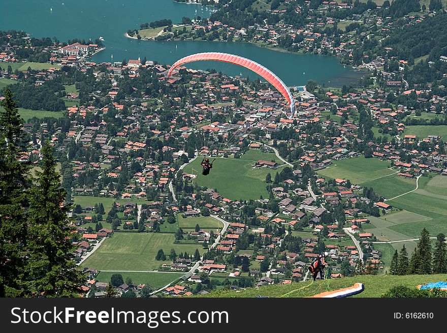 Plenty of paragliders are flying over a city in the Alps, Bavaria, Germany. Plenty of paragliders are flying over a city in the Alps, Bavaria, Germany
