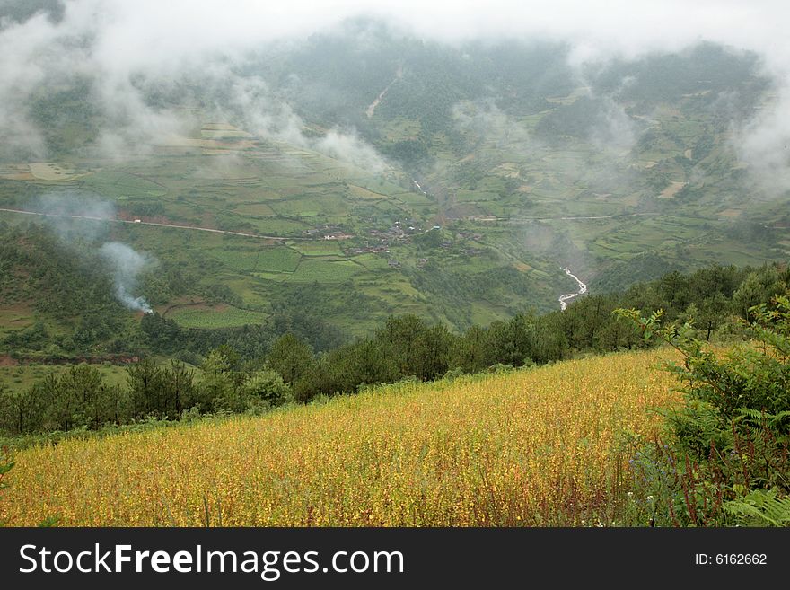 The photo is about Yunan province of China, there is a large field in front of a mountain, there are some clouds in the sky. The photo is about Yunan province of China, there is a large field in front of a mountain, there are some clouds in the sky.