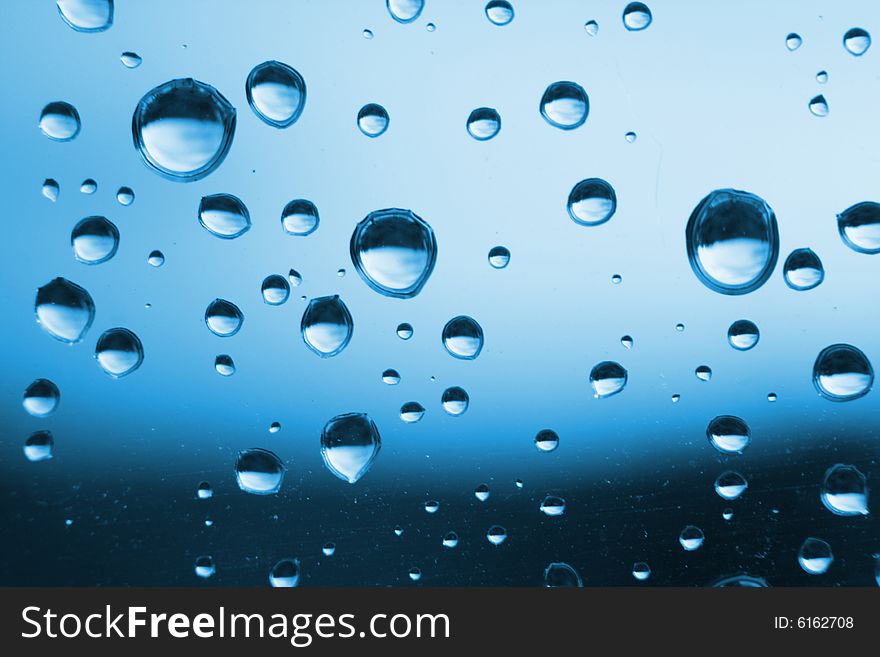 Blue water drops on the glass (abstract background)