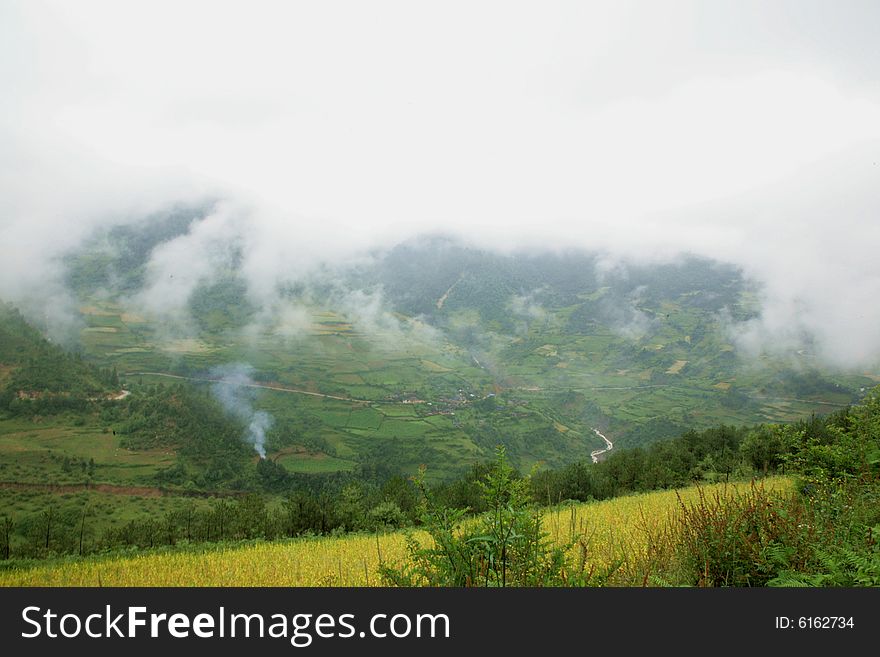 The photo is about Yunnan province of China, there is a large field in front of a mountain, there are some clouds in the sky. The photo is about Yunnan province of China, there is a large field in front of a mountain, there are some clouds in the sky.