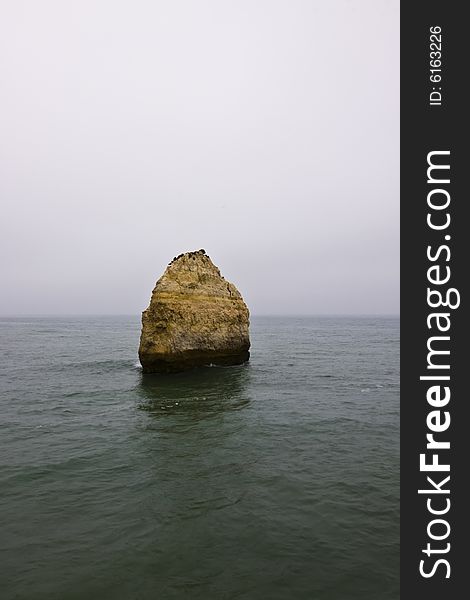 Big rock in the middle of the ocean barely seen due the myst. Big rock in the middle of the ocean barely seen due the myst.