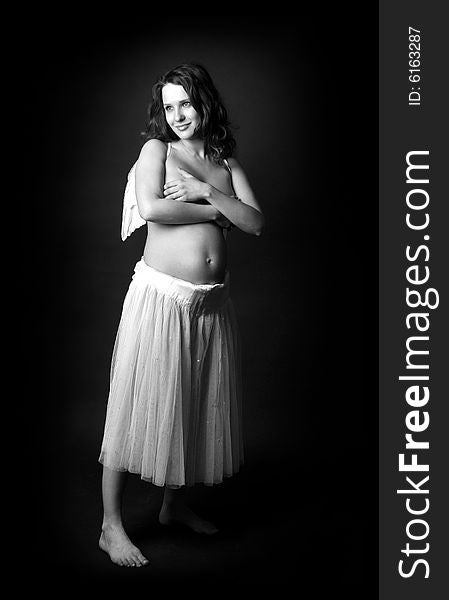 Pregnant woman on a black background with angel wings