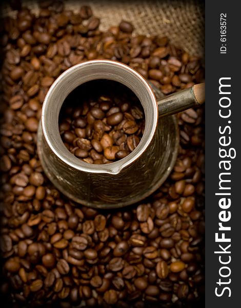 Cezve with freshly roasted coffee beans on sackcloth. Shallow depth of field. Focus on cezve throat. Cezve with freshly roasted coffee beans on sackcloth. Shallow depth of field. Focus on cezve throat