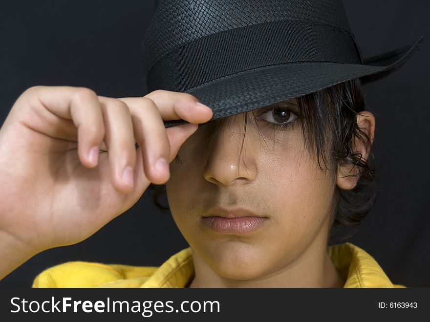 Teenager with black hat isolated on black background. Teenager with black hat isolated on black background