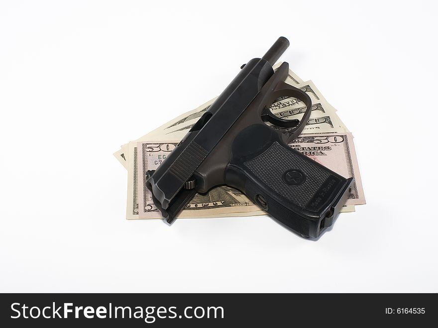 The pistol lays on dollar banknotes on a white background. The pistol lays on dollar banknotes on a white background