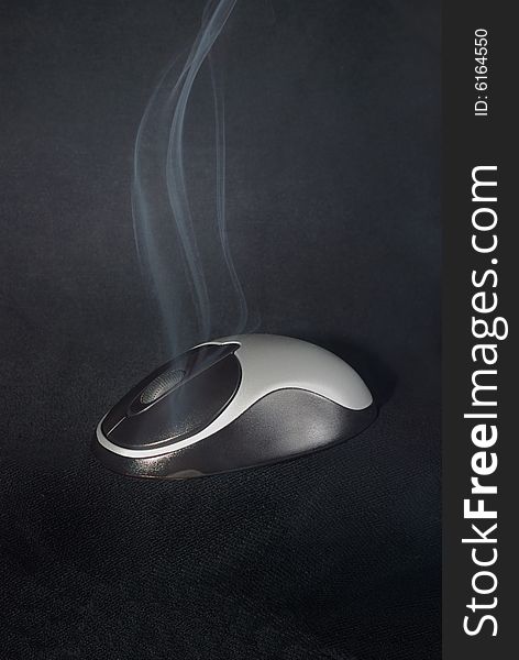 Black and silvery wireless wheel mouse smoking on black background. Black and silvery wireless wheel mouse smoking on black background