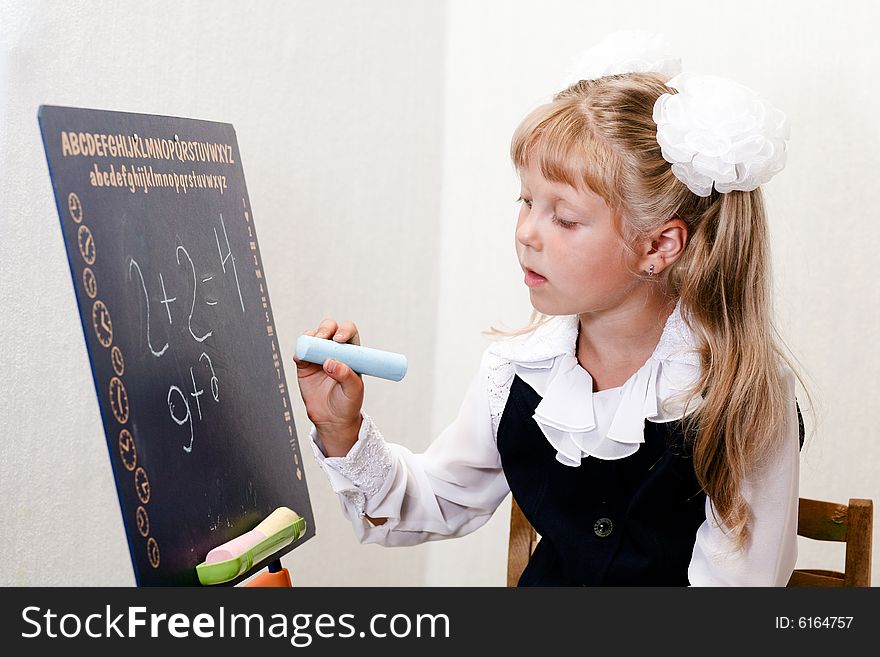 An image of nice little girl in shool writing on chalkboard. An image of nice little girl in shool writing on chalkboard.