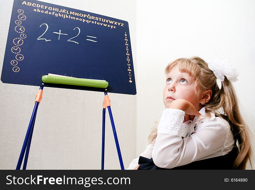 An image of Little girl sitting near chalkboard. An image of Little girl sitting near chalkboard.