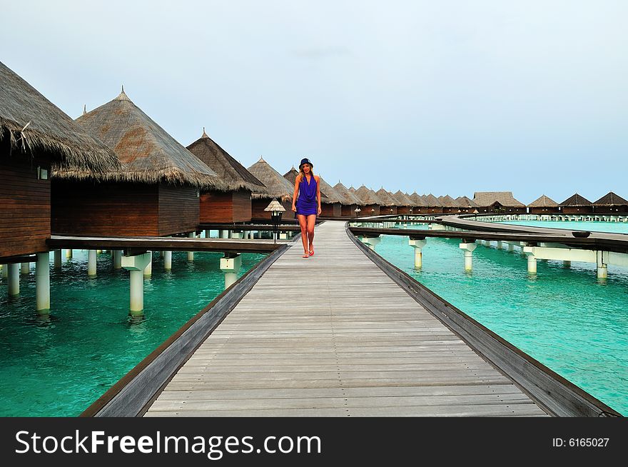 Woman walking on the deck leading to the bungalows on the water