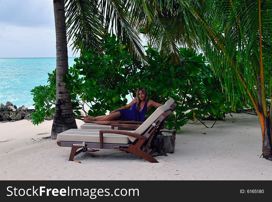 Woman lying on chaise longue on the tropical beach