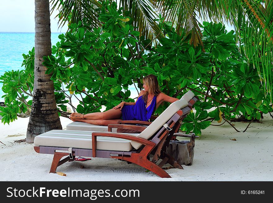 Woman lying on chaise longue on the tropical beach