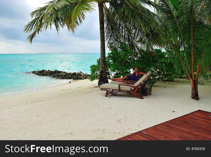 Woman lying on chaise longue on the tropical beach