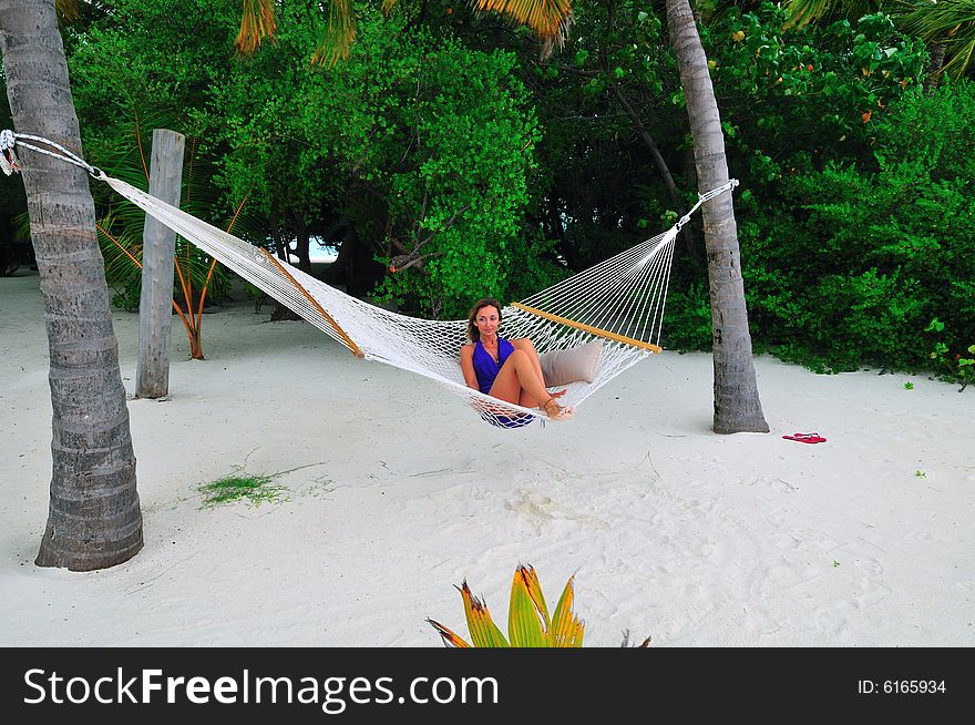 Woman lying on the hammock on a sandy beach in a resort in Maldives