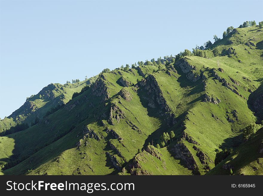 Mountains with green forest on blue sky. Mountains with green forest on blue sky