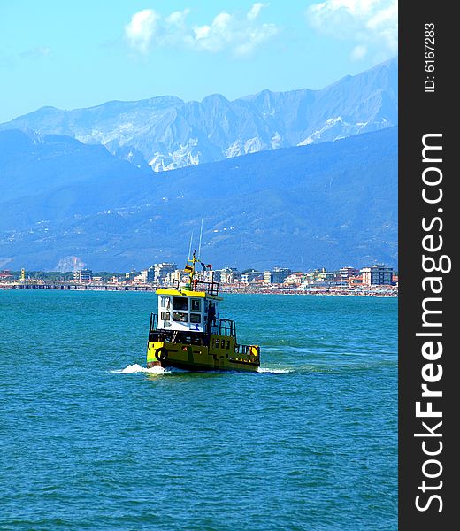 A beautiful shot of a fishing boat in the sea with Viareggio coast on the background. A beautiful shot of a fishing boat in the sea with Viareggio coast on the background