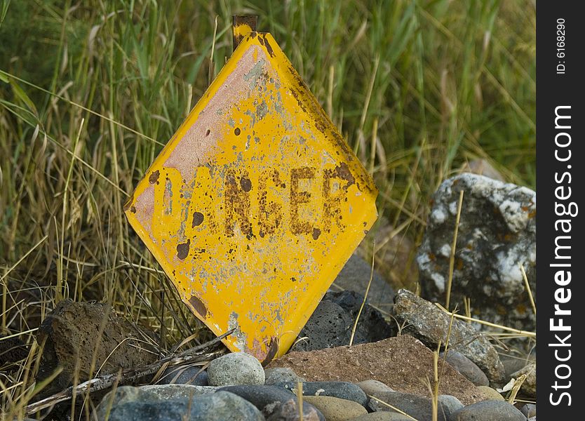 Rusty danger sign with missing letters.