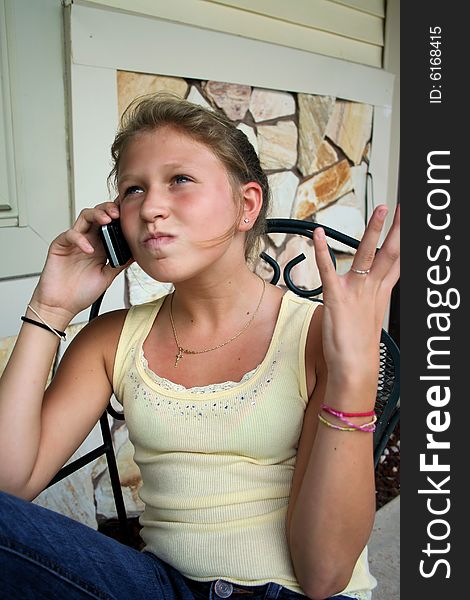 Photo of a 12 year old beautiful girl talking on her cell phone to her friends. Photo of a 12 year old beautiful girl talking on her cell phone to her friends