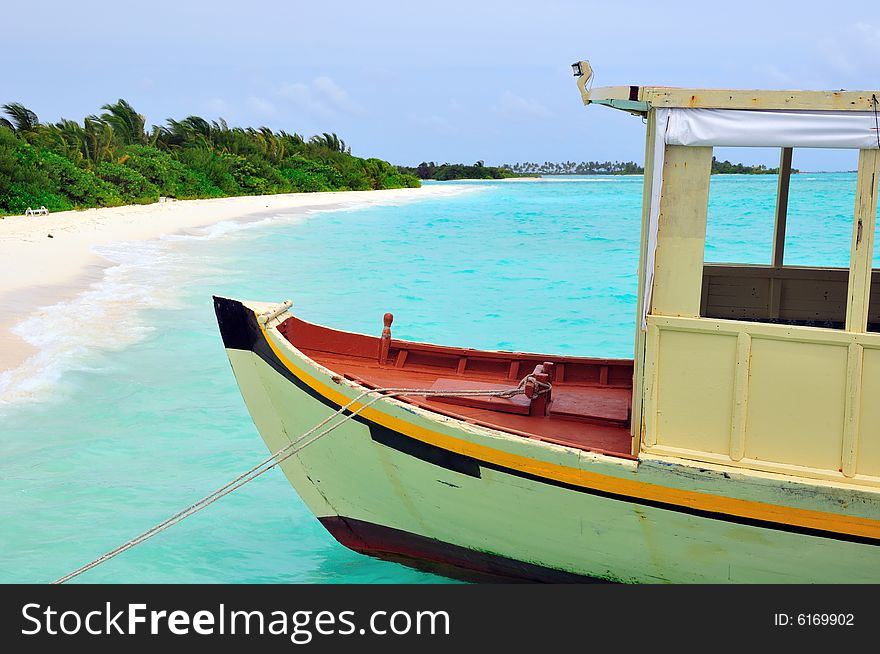 Old traditional boat anchored on a sandy beach in Maldives