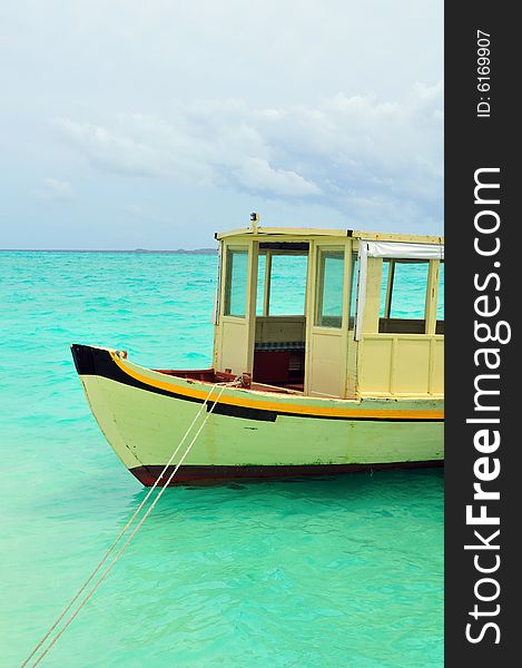 Old traditional boat anchored on a sandy beach in Maldives