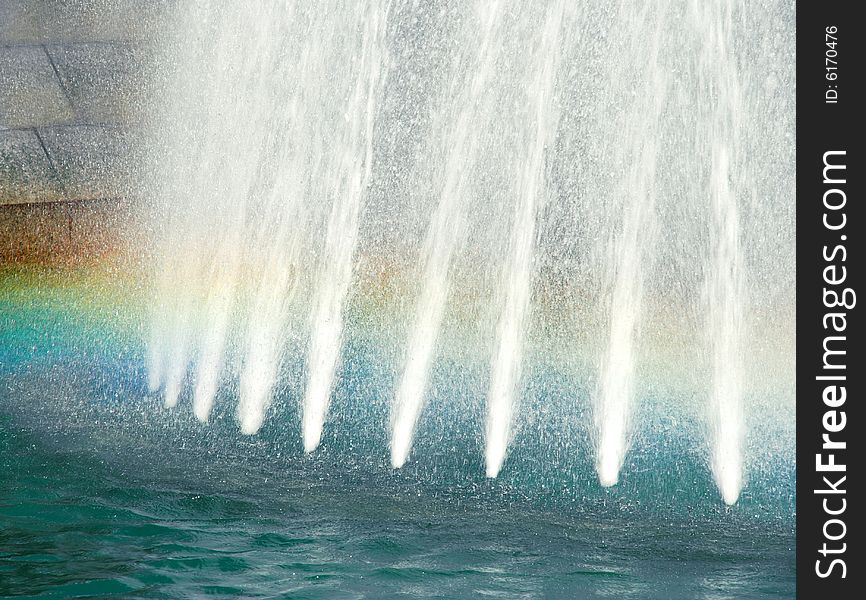 Water white streams in blue fountain with rainbow