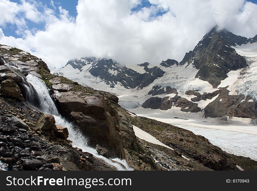 Waterfall and high mountains with glacier on background. Waterfall and high mountains with glacier on background