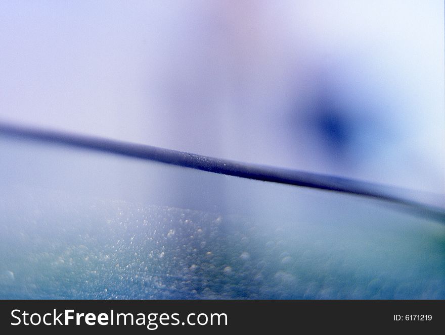 Blue and aqua abstract textured background with horizontal slightly diagonal line with glass texture in bottom half and blue spot in top half. Blue and aqua abstract textured background with horizontal slightly diagonal line with glass texture in bottom half and blue spot in top half