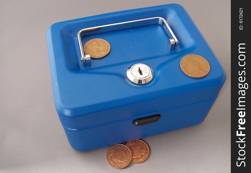 A blue money box with low denomination coins scattered around it.