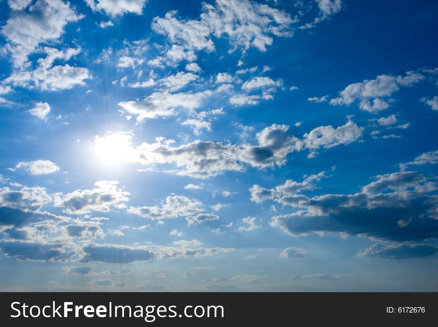 Cloudscape with sun in blue sky