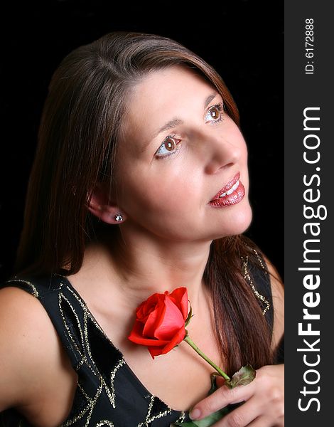 Brunette model holding a red rose, looking into the distance