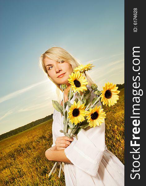 Young beautiful woman with a bouquet of sunflowers in the field. Young beautiful woman with a bouquet of sunflowers in the field