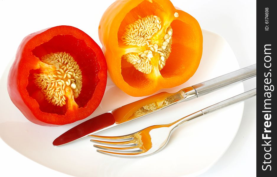 Pepper on a white plate, a knife and a fork. Pepper on a white plate, a knife and a fork