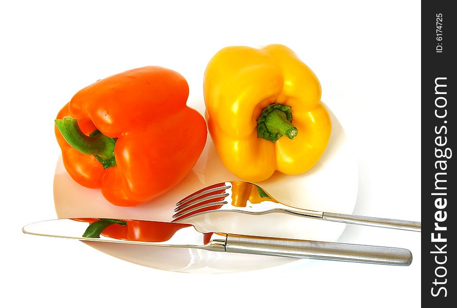Pepper on a white plate, a knife and a fork