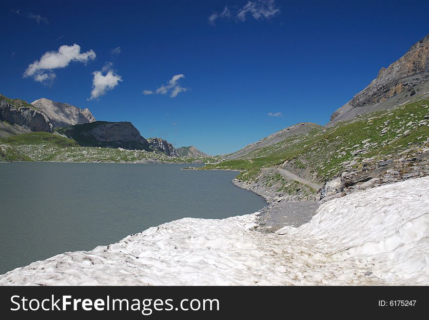 A  view on mountains lake in Swiss Alps under deep blue sky, horizontal. A  view on mountains lake in Swiss Alps under deep blue sky, horizontal.