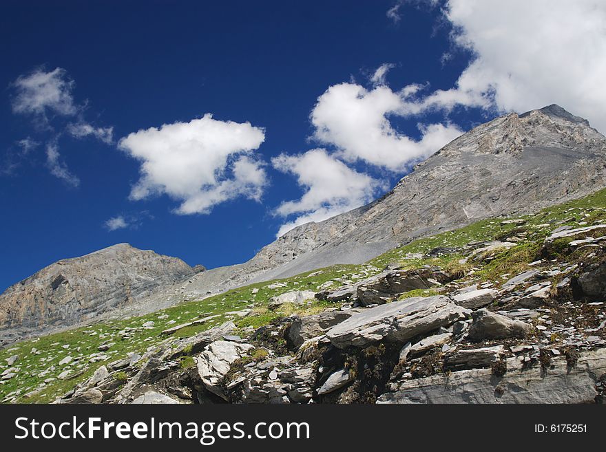 High mountain landscape with deep blue sky, clouds and many big rocks in front, horizontal. High mountain landscape with deep blue sky, clouds and many big rocks in front, horizontal