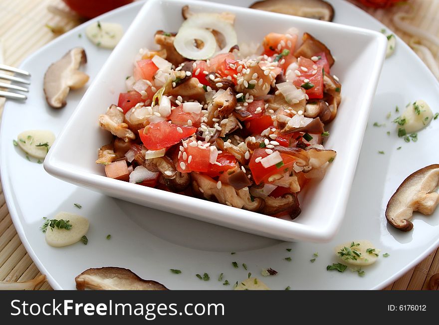 A salad of mushrooms and tomatoes with sesame seeds