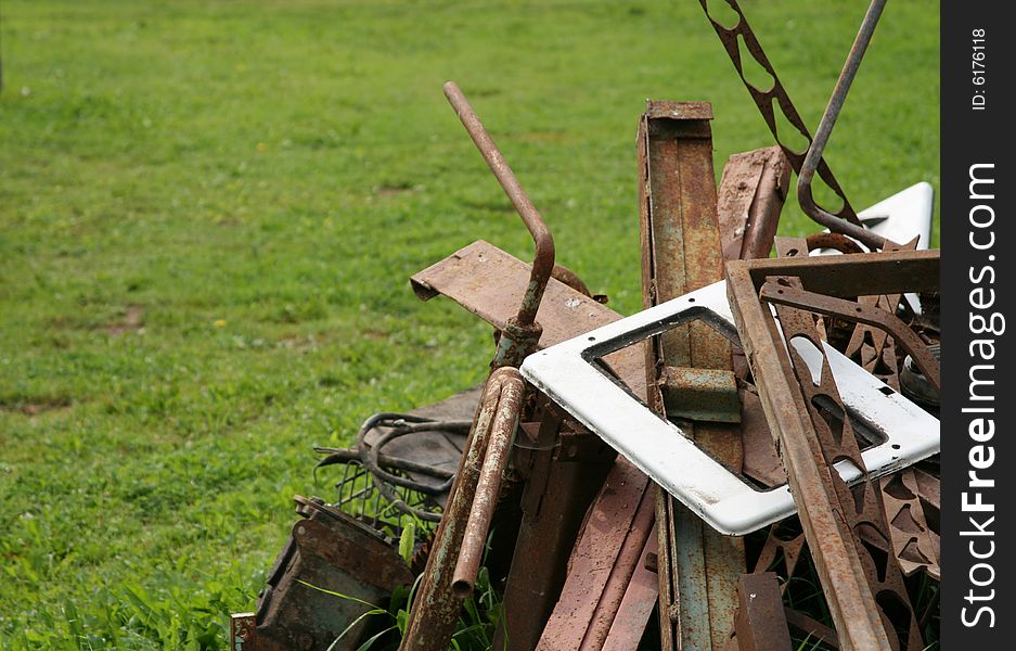 The dump with old rusty parts and green grass as a background