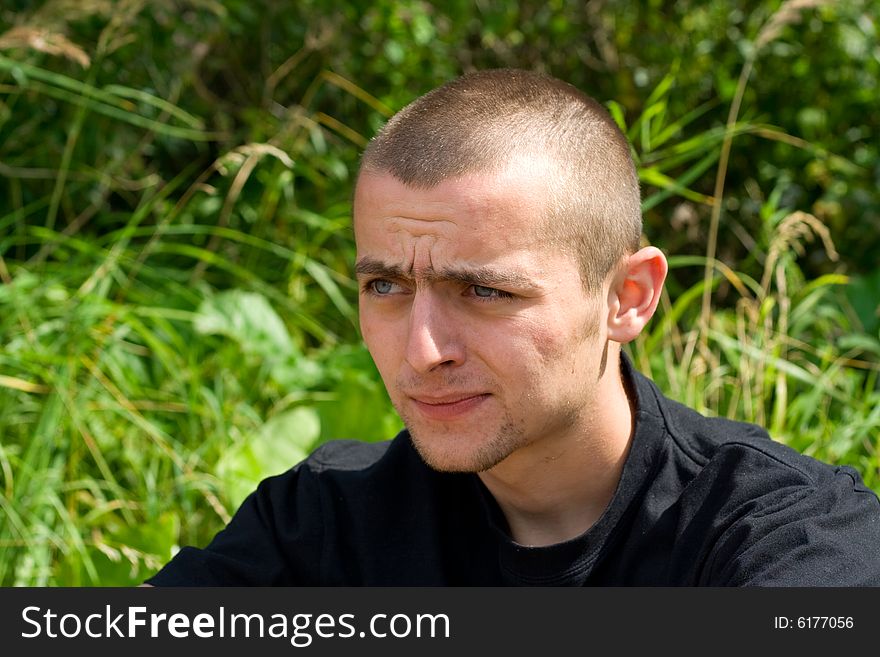 Man sitting on the background of green grass portrait