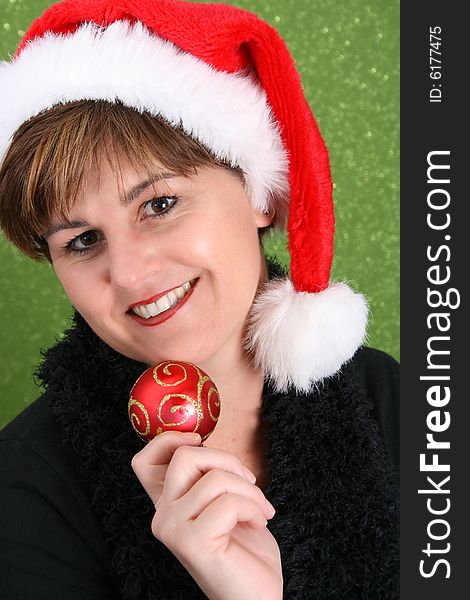 Adult female wearing a christmas hat, holding a decoration. Adult female wearing a christmas hat, holding a decoration