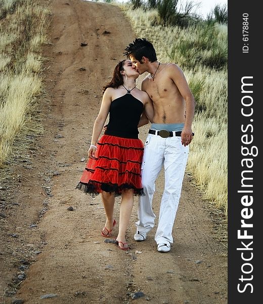 A boy and a girl kissing on a country road. A boy and a girl kissing on a country road.