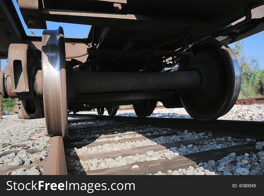 Looking up at a rusty freight train car with wheels polished to a shiny finish by the railroad tracks underneath. Looking up at a rusty freight train car with wheels polished to a shiny finish by the railroad tracks underneath