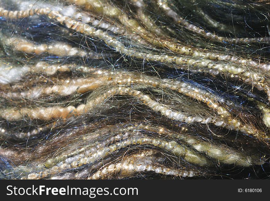 Close-up (macro) of blue and yellow mohair yarn wrapped in gold strands, forming wavy lines. Close-up (macro) of blue and yellow mohair yarn wrapped in gold strands, forming wavy lines