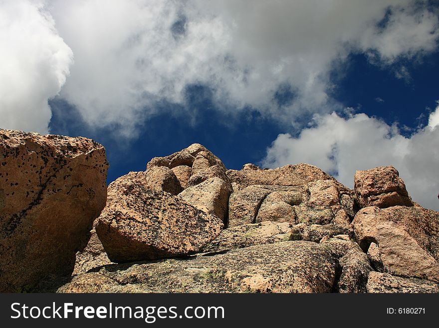 View of pinkish granite rock formation looking upwards against blue sky and white clouds