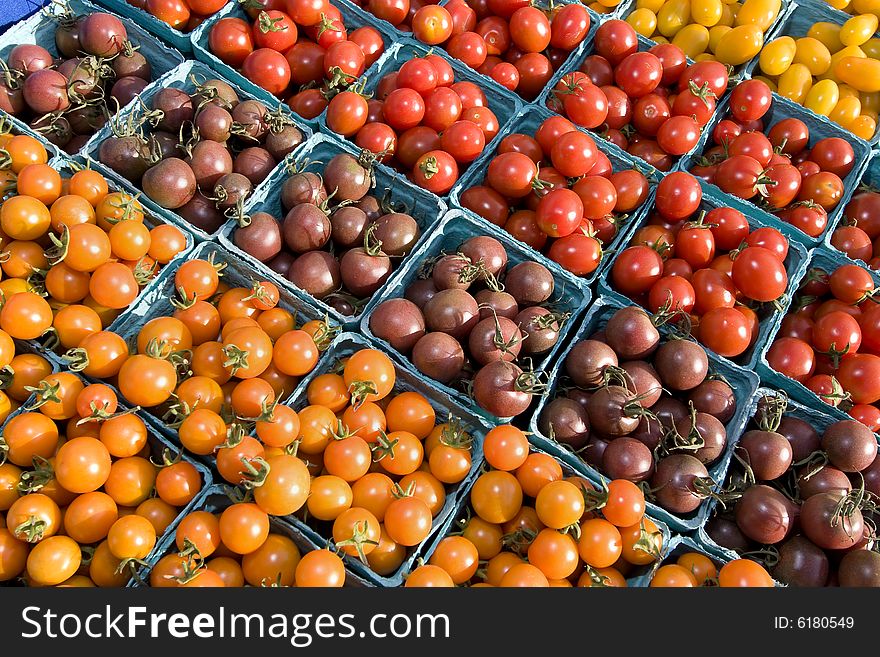 Baskets of red, yellow, purple, and grape tomatoes. Horizontally framed photo. Baskets of red, yellow, purple, and grape tomatoes. Horizontally framed photo.