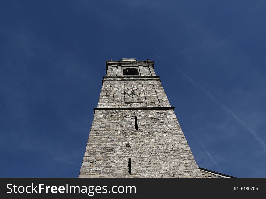 Main Tower of a church made of stone in Bellagio, Italy on Como lake, on blue sky foreground. Main Tower of a church made of stone in Bellagio, Italy on Como lake, on blue sky foreground