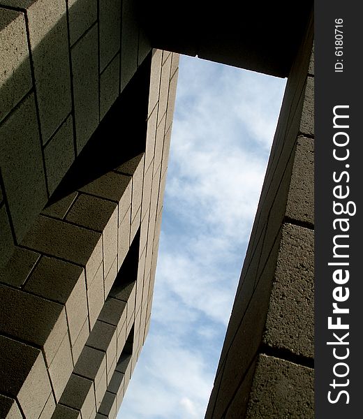 View from below a building with the sky peeking through. Vertically framed photo. View from below a building with the sky peeking through. Vertically framed photo.