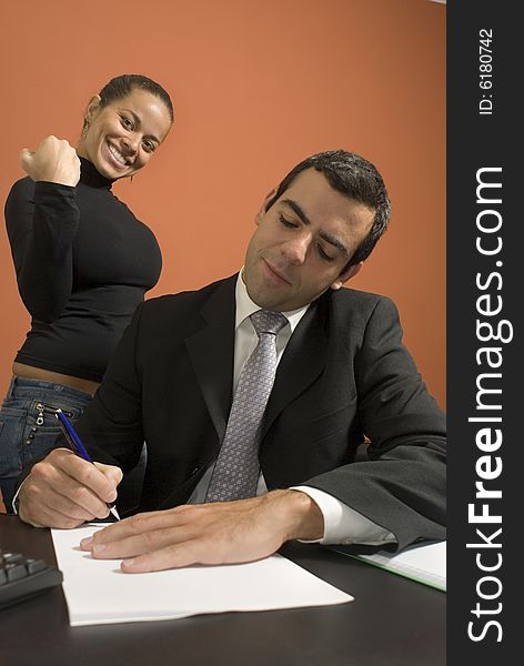 Businessman working at his desk while his co-worker pretends to be angry with him. Vertically framed photo. Businessman working at his desk while his co-worker pretends to be angry with him. Vertically framed photo