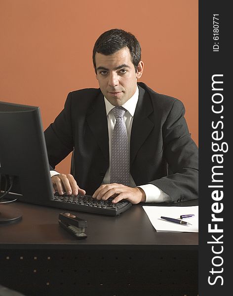 Businessman looking at his laptop computer at his desk. Vertically framed photograph. Businessman looking at his laptop computer at his desk. Vertically framed photograph.